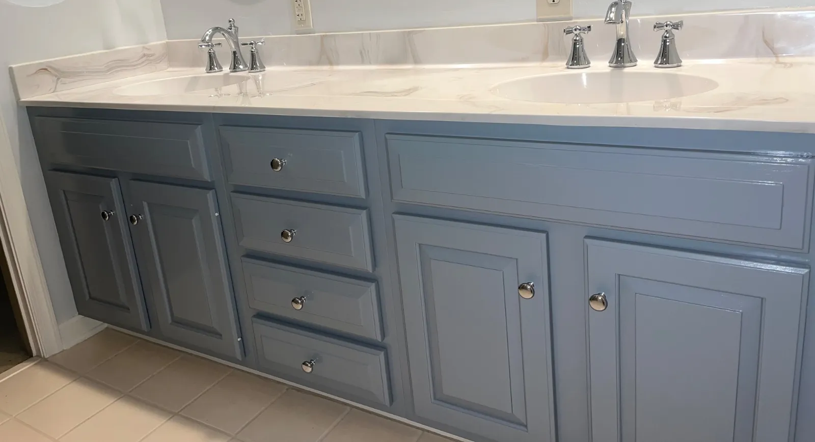 Double bathroom vanity painted blue-gray, with drawers, chrome knobs and two sinks